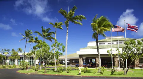 Front entrance with flags and palms at Hilton Garden Inn Kauai Wailua Bay.