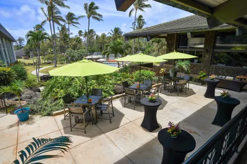 Patio tables with green umbrellas at Hilton Garden Inn Kauai Wailua Bay.