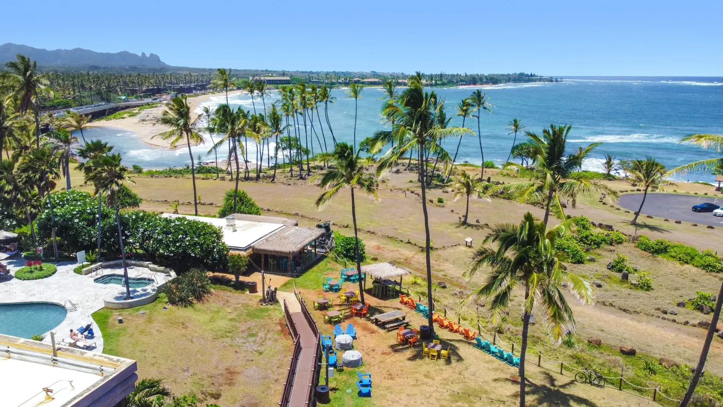 Oceanfront lawn, pool edge, and beach view at Hilton Garden Inn Kauai Wailua Bay.