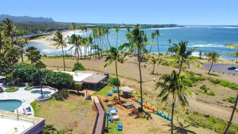 Oceanfront lawn, pool edge, and beach view at Hilton Garden Inn Kauai Wailua Bay.