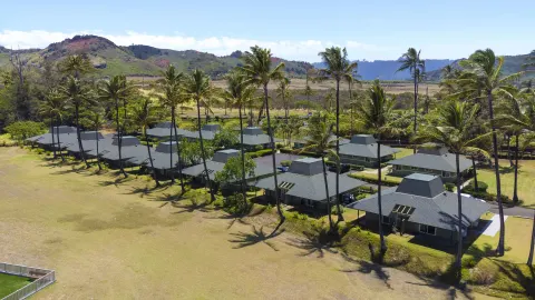 Palm-shaded cottages and mountain backdrop at Hilton Garden Inn Kauai Wailua Bay.