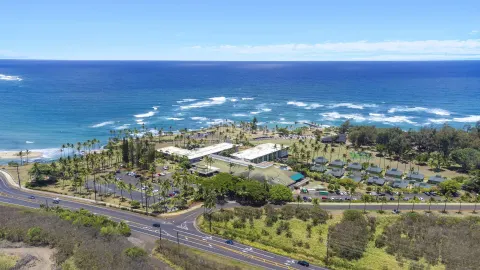 Wide aerial view of the resort, road, and ocean at Hilton Garden Inn Kauai Wailua Bay.