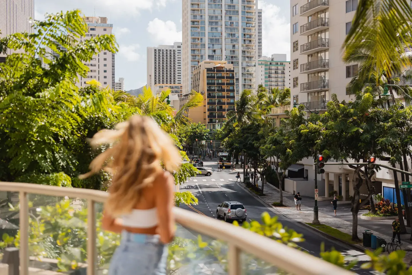 Guest on a balcony looking over Waikiki streets at Hilton Garden Inn Waikiki Beach.