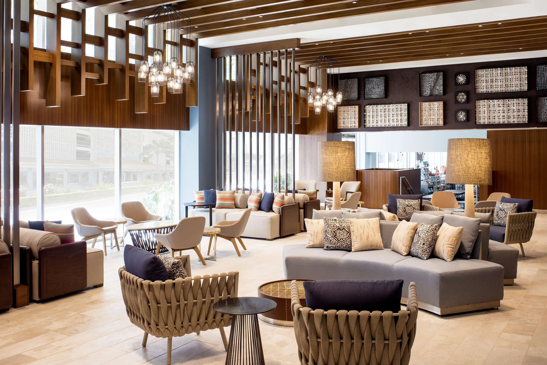 Bright lobby lounge with tall windows and chandeliers at Hilton Garden Inn Waikiki Beach.