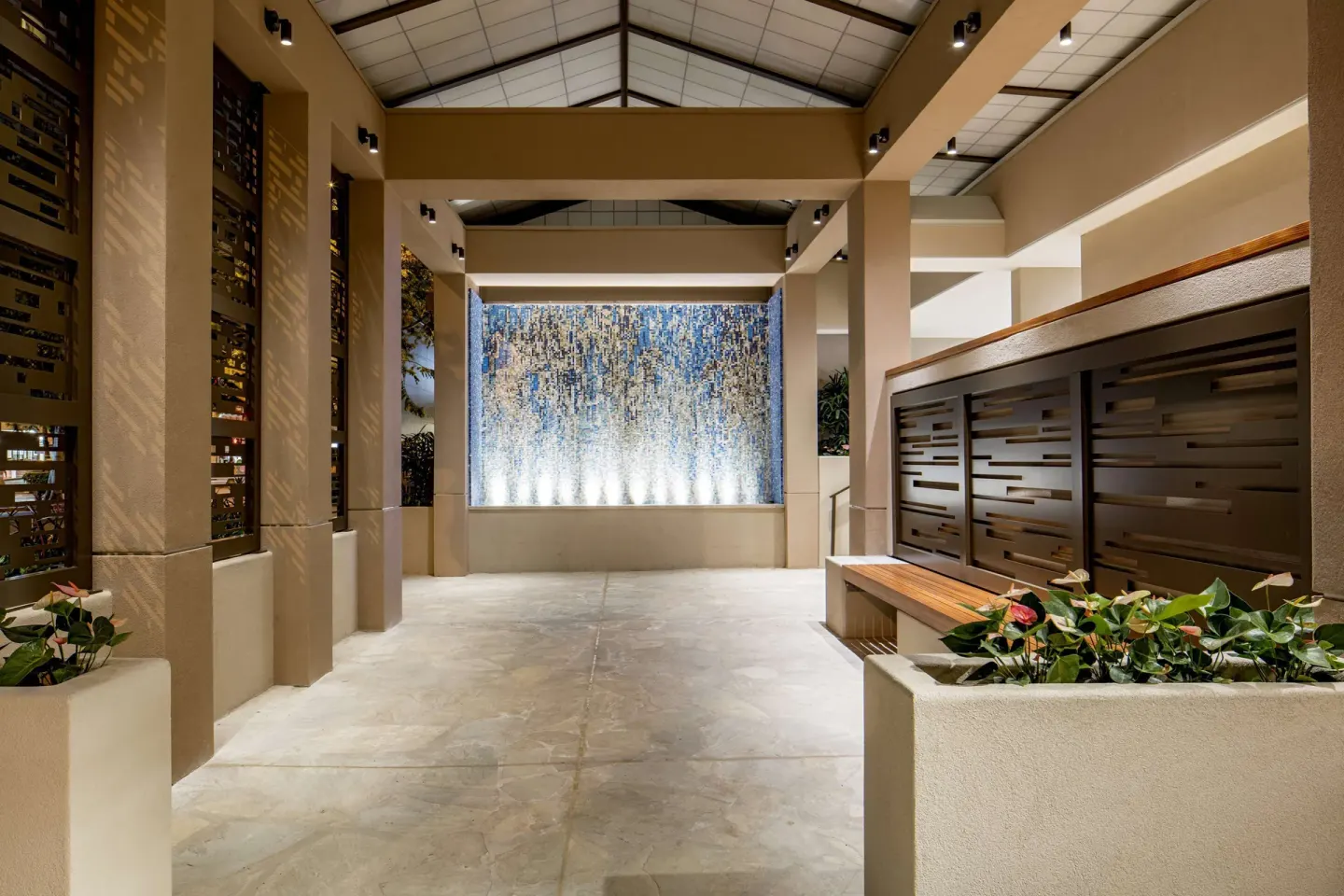 Covered entry walkway with lit mosaic wall at Hilton Garden Inn Waikiki Beach.