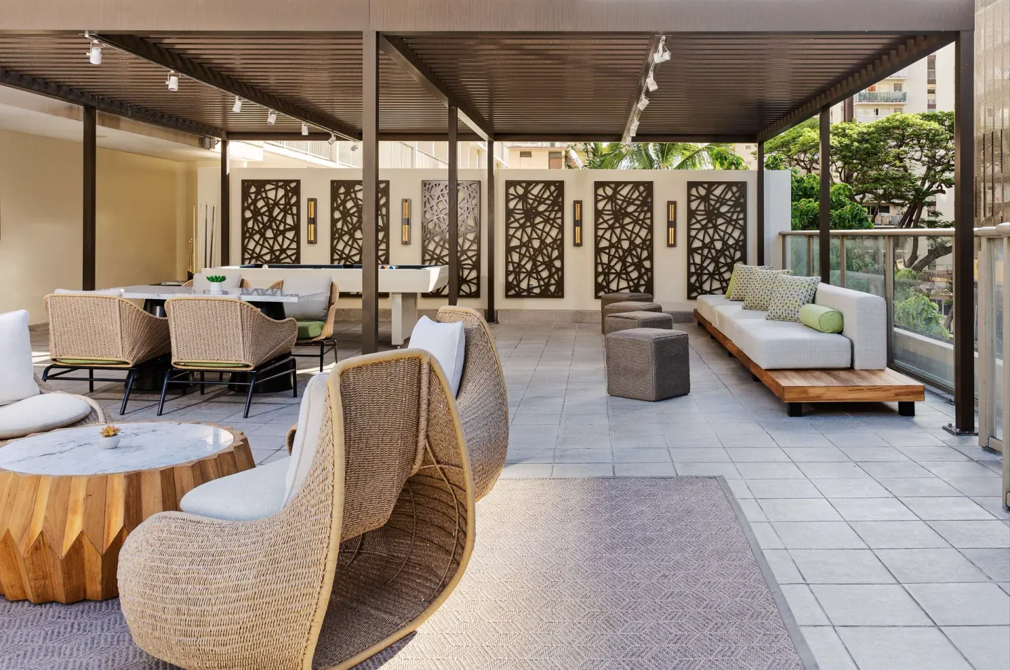 Covered terrace lounge with wicker chairs at Hilton Garden Inn Waikiki Beach.