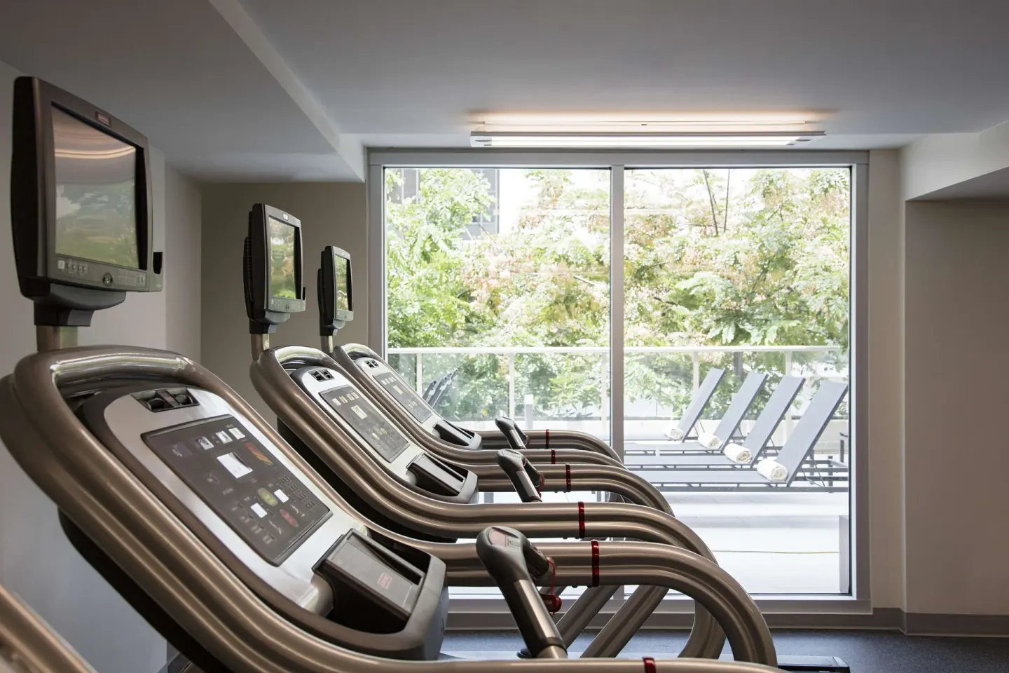 Treadmills facing large windows in the fitness center at Hilton Garden Inn Waikiki Beach.
