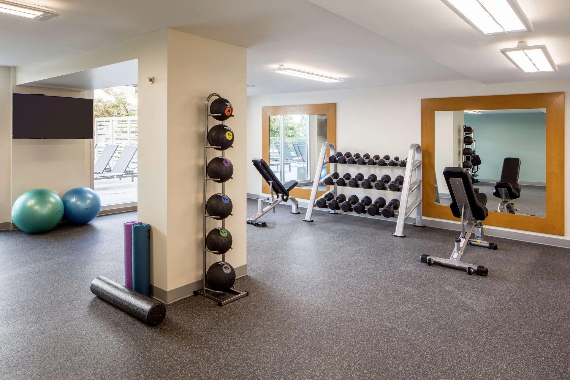 Fitness center with weights, benches, and exercise balls at Hilton Garden Inn Waikiki Beach.