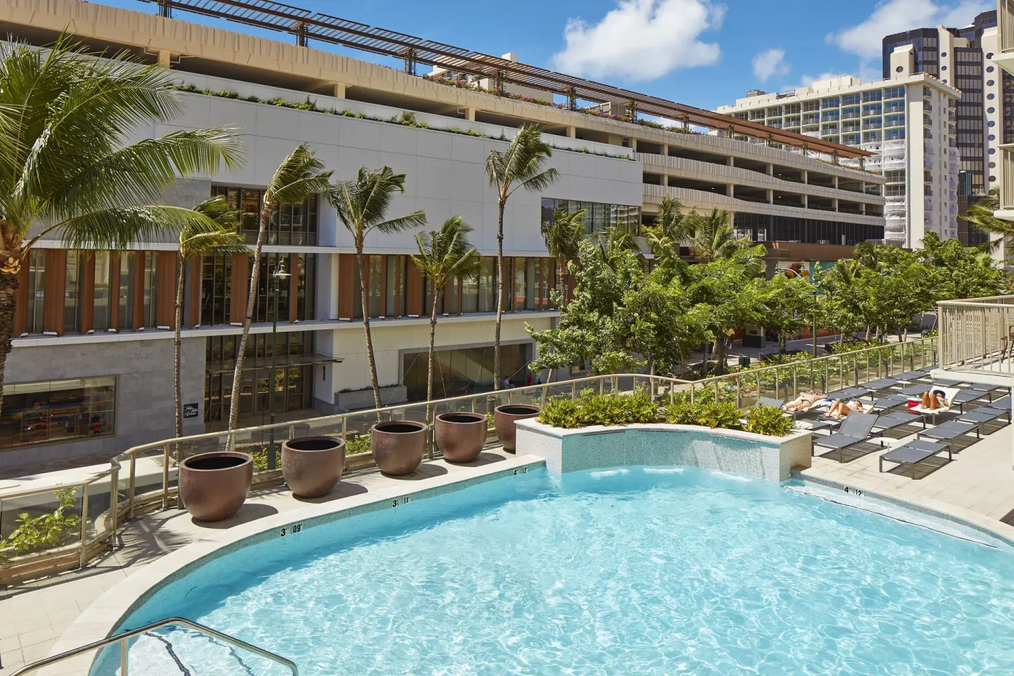 Outdoor pool deck with loungers at Hilton Garden Inn Waikiki Beach.