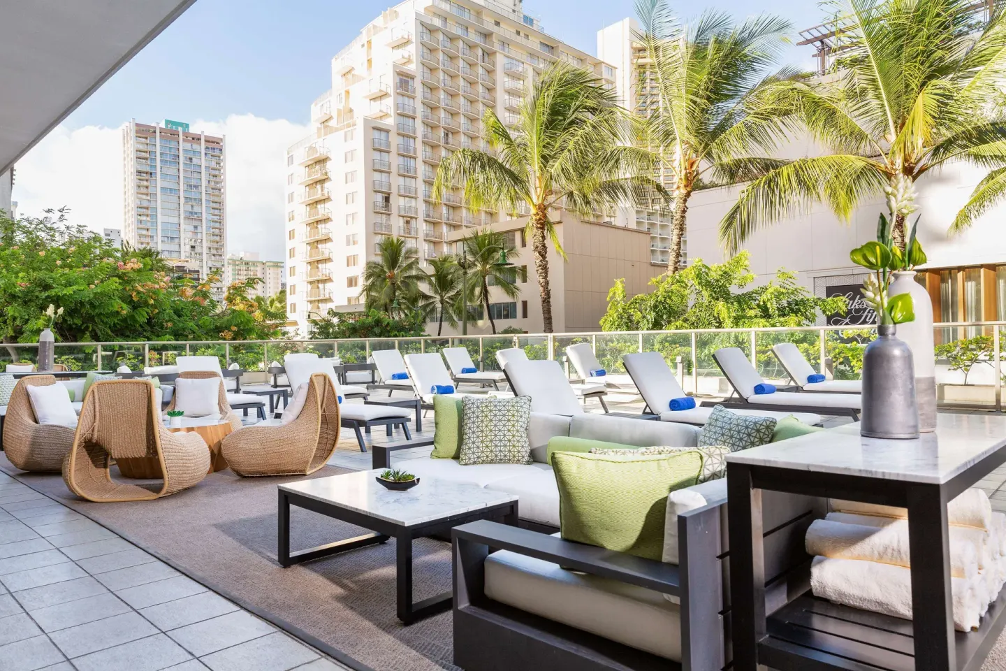 Pool deck lounge chairs and seating with palm trees at Hilton Garden Inn Waikiki Beach.