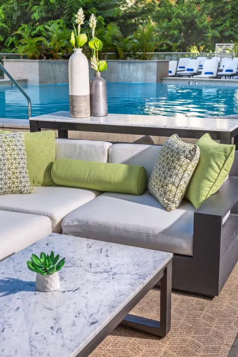 Poolside sofa with green pillows beside the pool at Hilton Garden Inn Waikiki Beach.