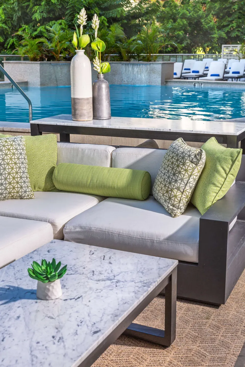 Poolside sofa with green pillows beside the pool at Hilton Garden Inn Waikiki Beach.
