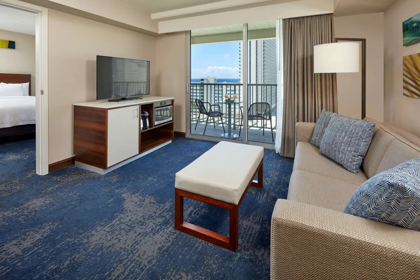Suite sitting room with sofa and balcony at Hilton Garden Inn Waikiki Beach.