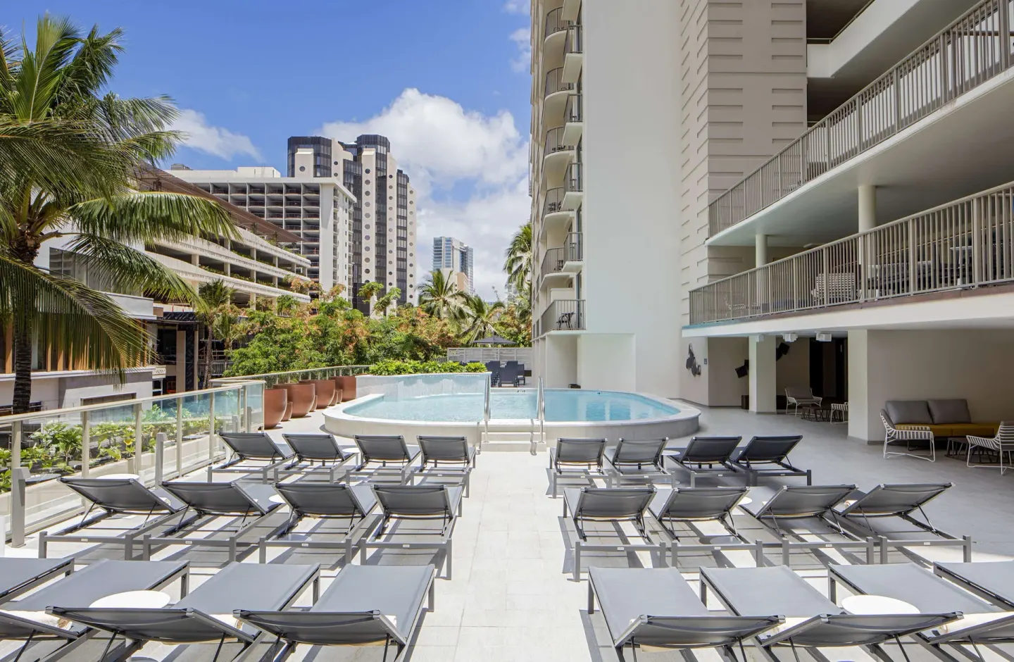 Sunny pool deck with rows of lounge chairs at Hilton Garden Inn Waikiki Beach.
