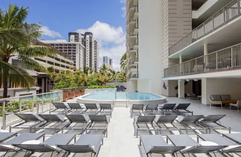 Sunny pool deck with rows of lounge chairs at Hilton Garden Inn Waikiki Beach.