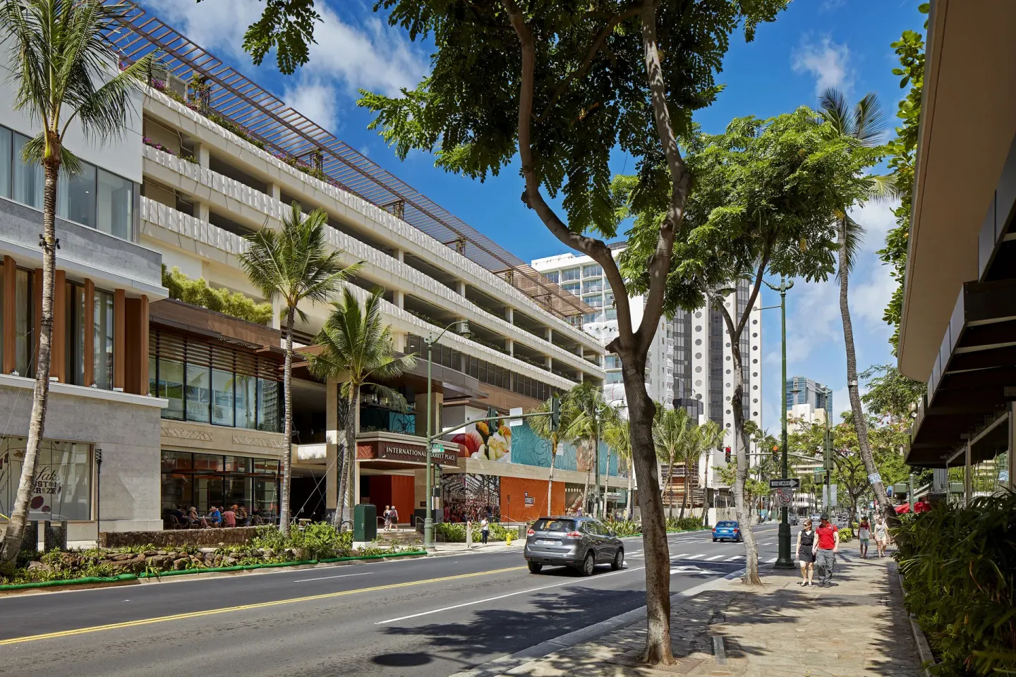 Waikiki street scene with trees and nearby shops at Hilton Garden Inn Waikiki Beach.