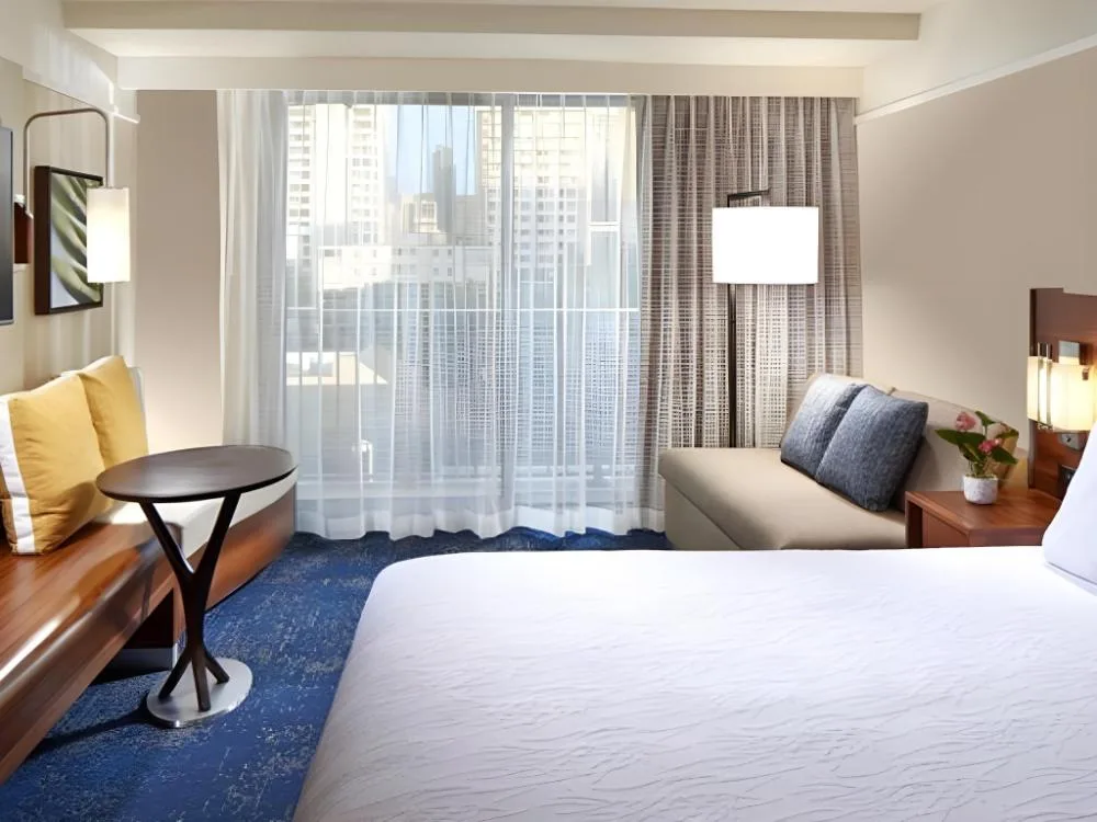 King guest room with sofa and city-facing window at Hilton Garden Inn Waikiki Beach.