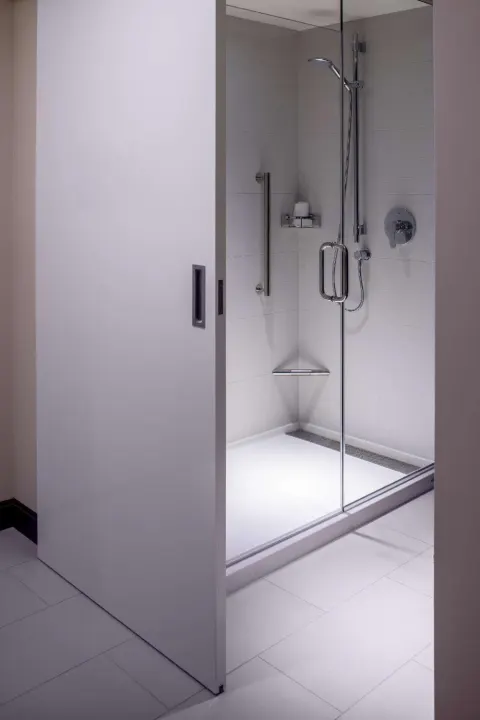 Accessible guest bathroom shower with glass door and grab bars at Hilton Garden Inn Waikiki Beach.
