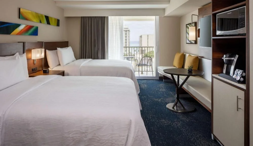 Two-bed hearing accessible partial ocean view room at Hilton Garden Inn Waikiki Beach with balcony.
