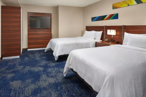 Accessible city view hearing room with two beds and wall-mounted TV at Hilton Garden Inn Waikiki Beach.