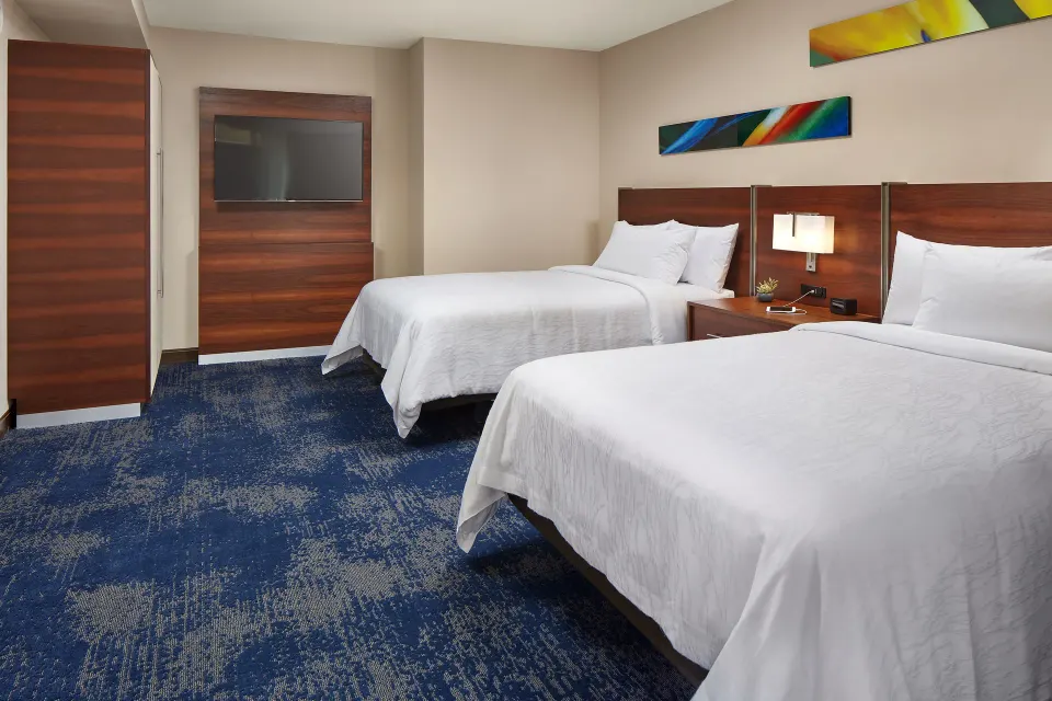 Accessible city view hearing room with two beds and wall-mounted TV at Hilton Garden Inn Waikiki Beach.