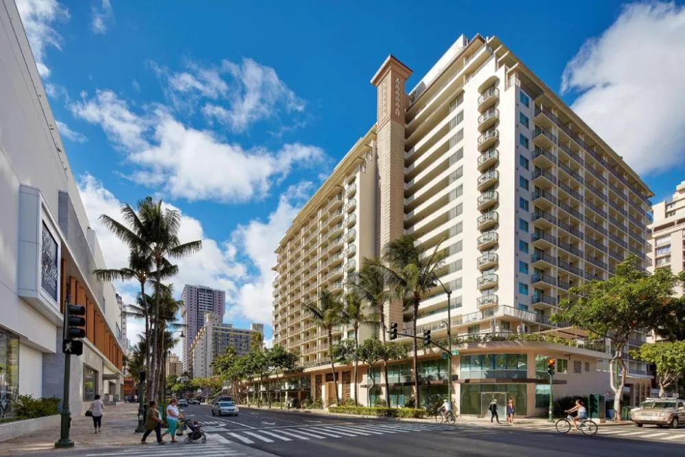 Street view of the exterior tower and palms at Hilton Garden Inn Waikiki Beach.