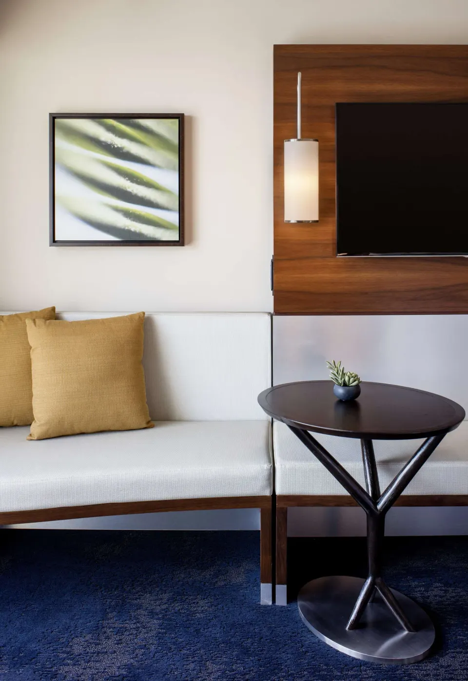 Standard Room sofa bed seating, round table, wall art, and TV at Hilton Garden Inn Waikiki Beach.