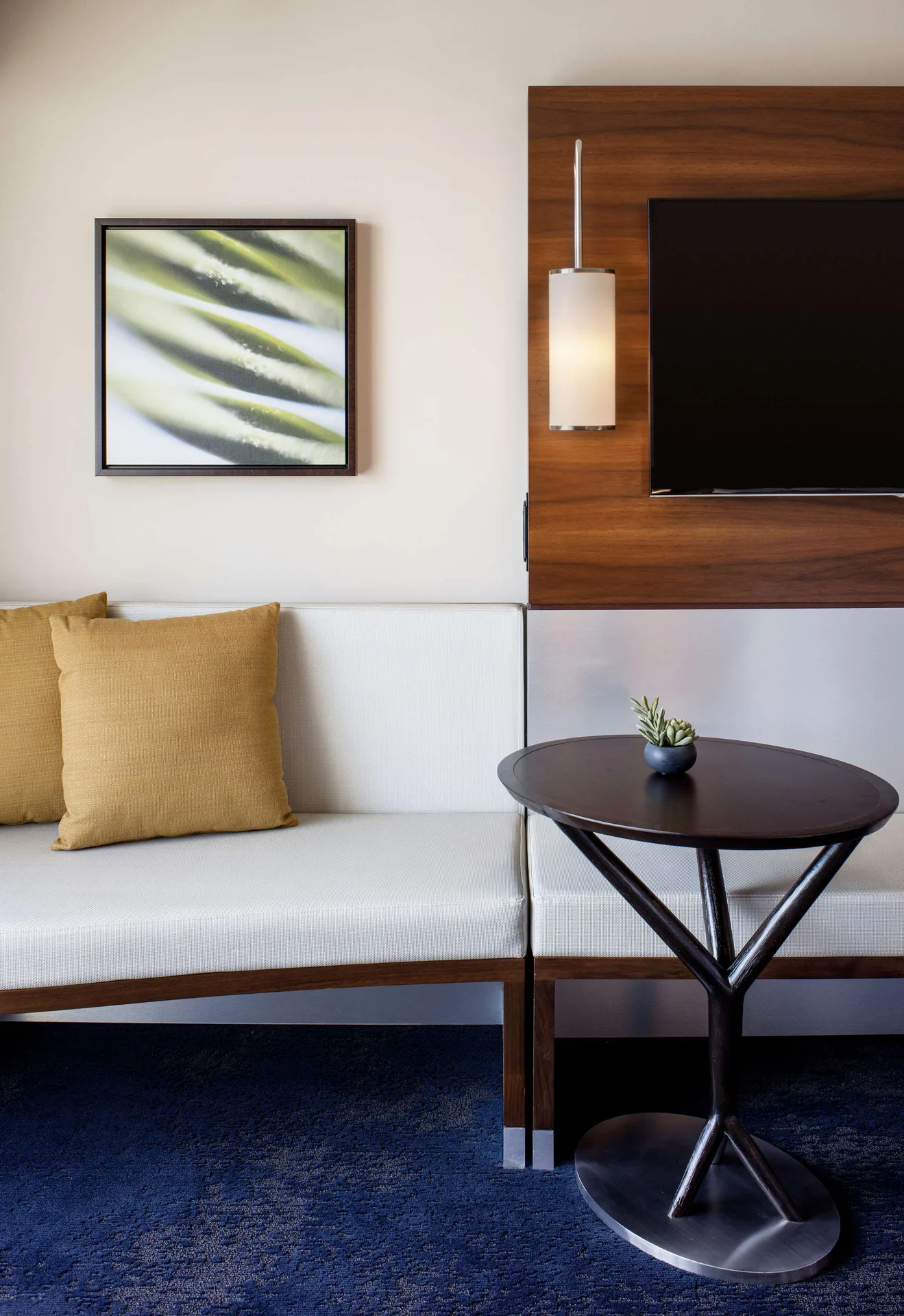 Standard Room sofa bed seating, round table, wall art, and TV at Hilton Garden Inn Waikiki Beach.