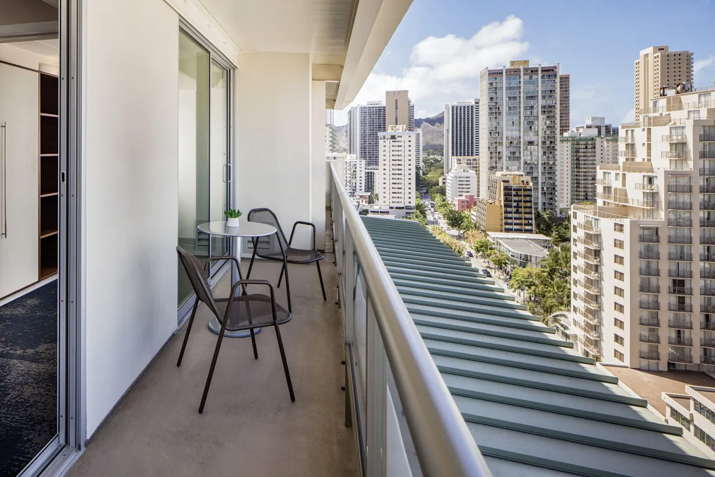 Accessible suite balcony with table, chairs, and Waikiki city views at Hilton Garden Inn Waikiki Beach.