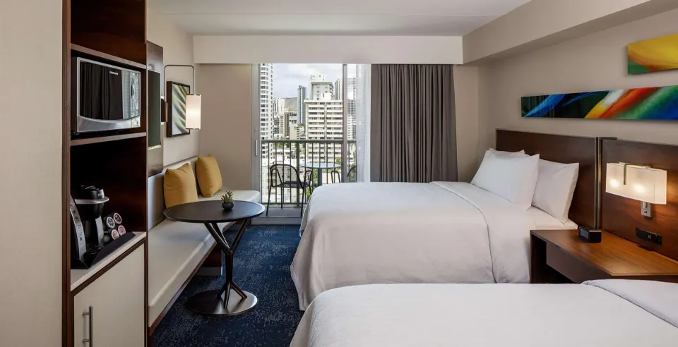 Accessible suite with two beds, dining nook, microwave, and balcony at Hilton Garden Inn Waikiki Beach.