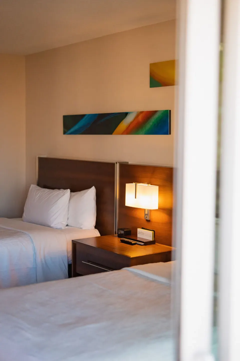 Accessible suite bedroom with two beds and a lit nightstand at Hilton Garden Inn Waikiki Beach.