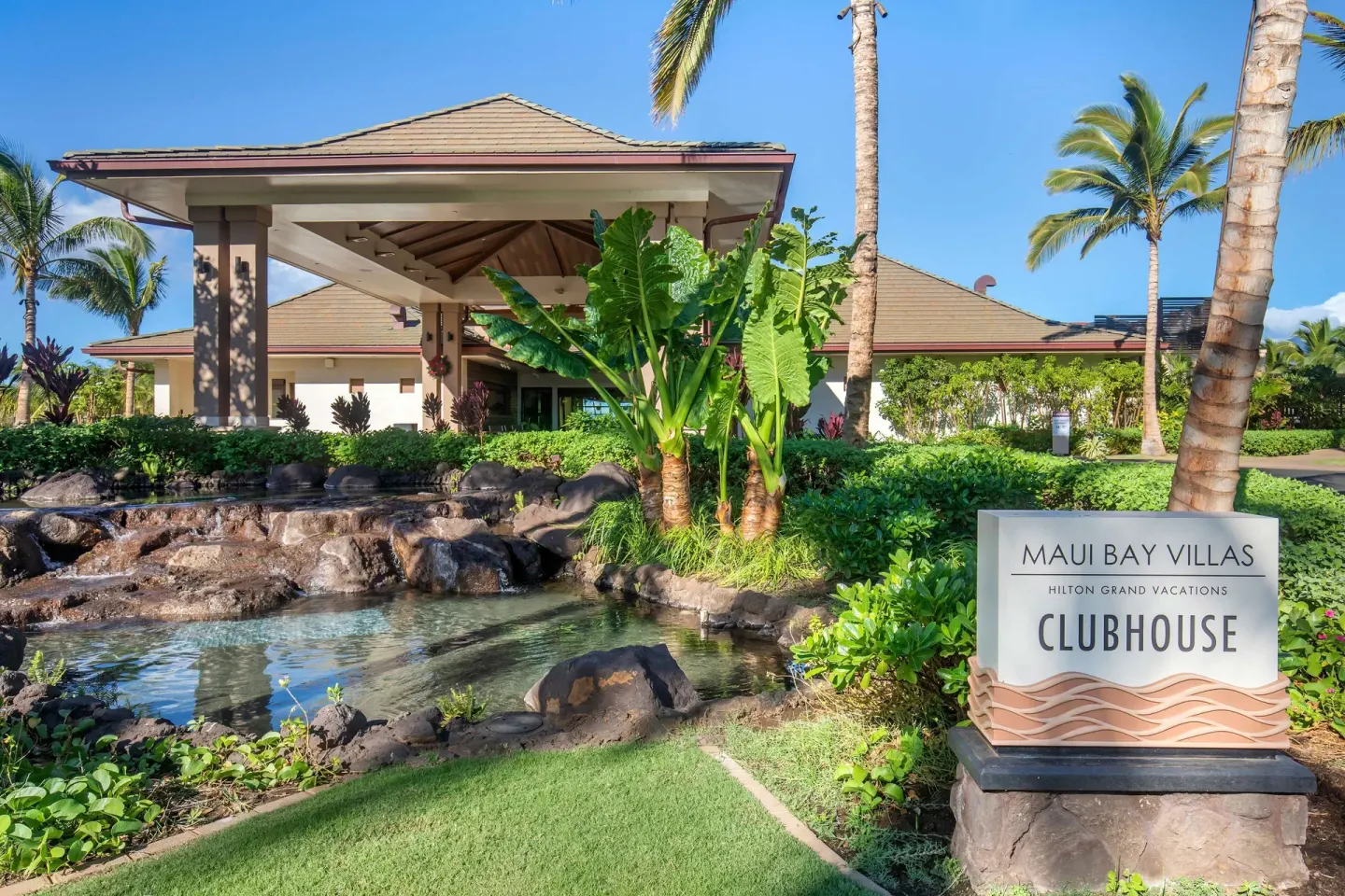 Clubhouse entrance at Hilton Grand Vacations Club Maui Bay Villas beside a pond and tropical landscaping.