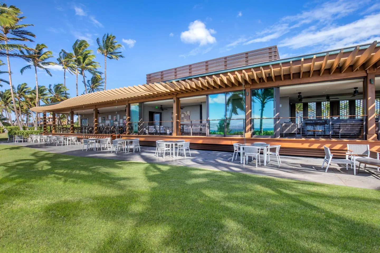 Outdoor terrace and lawn at Hilton Grand Vacations Club Maui Bay Villas with palms and white seating.