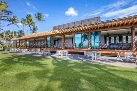 Outdoor terrace and lawn at Hilton Grand Vacations Club Maui Bay Villas with palms and white seating.