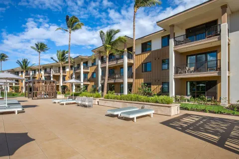 Resort courtyard at Hilton Grand Vacations Club Maui Bay Villas with balconies, loungers, and palm trees.