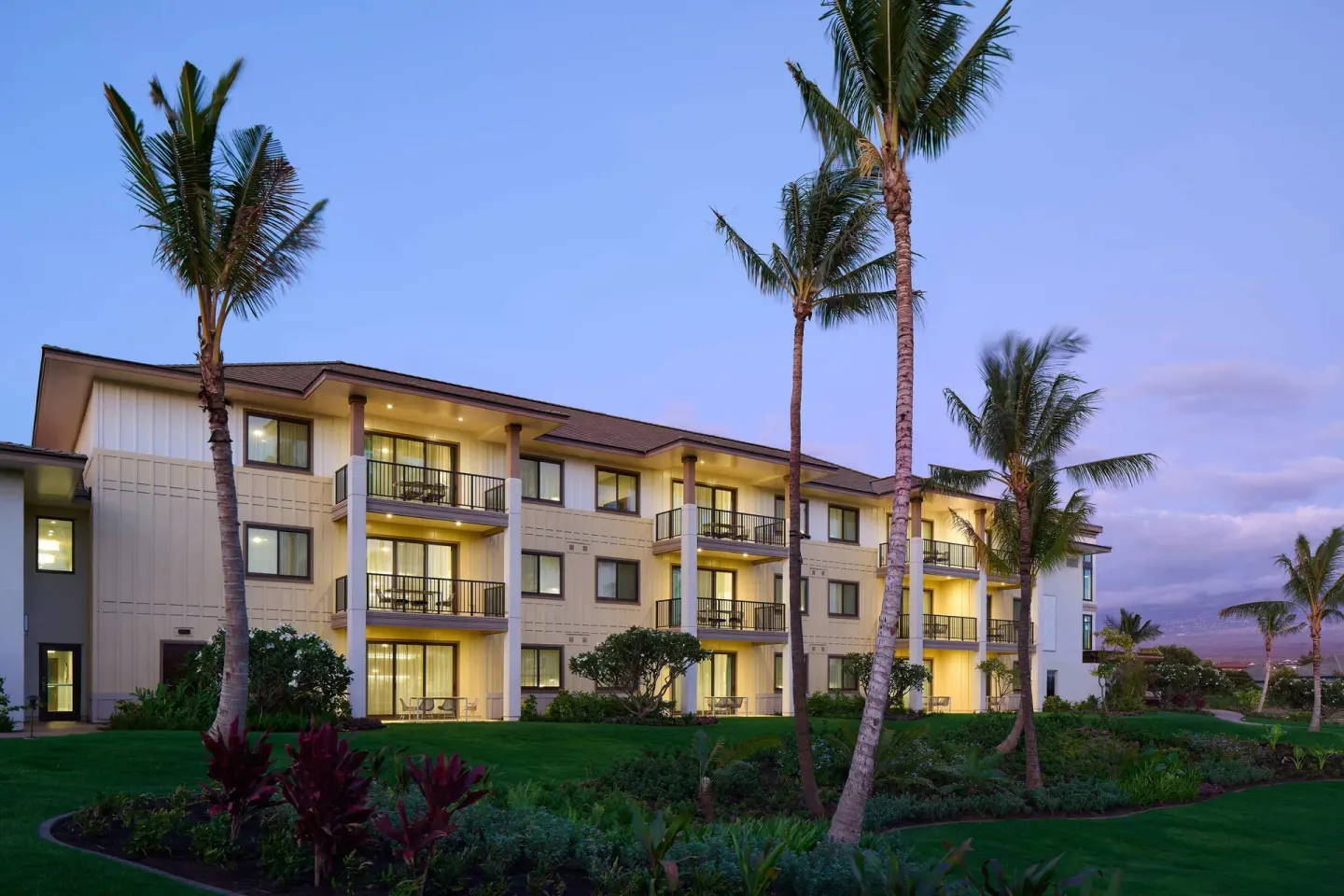 Exterior resort building and palms at dusk at Hilton Grand Vacations Club Maui Bay Villas.