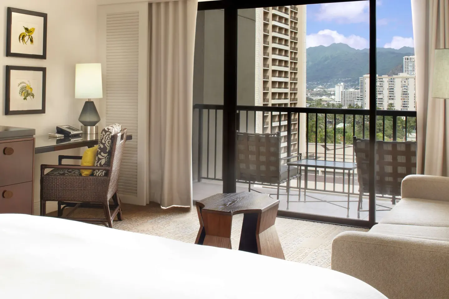 Guest room with balcony views of Waikiki buildings and mountains at Hilton Hawaiian Village Waikiki Beach Resort.