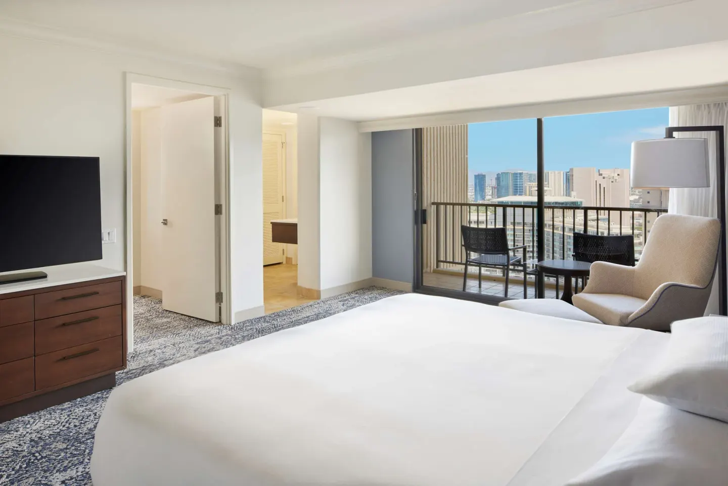 King-bed guest room with balcony seating and city view at Hilton Hawaiian Village Waikiki Beach Resort.