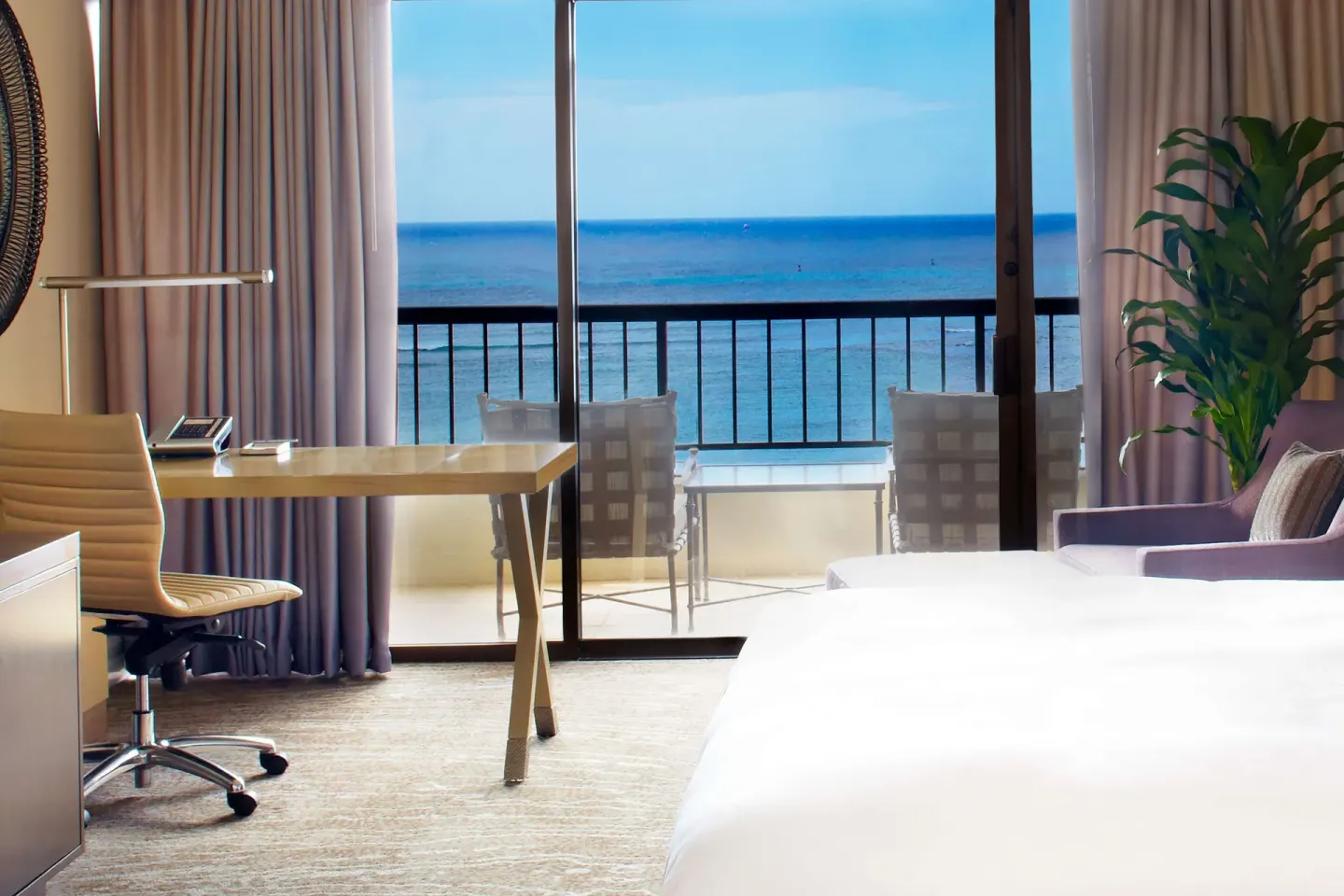 Ocean view guest room with balcony chairs and work desk at Hilton Hawaiian Village Waikiki Beach Resort.