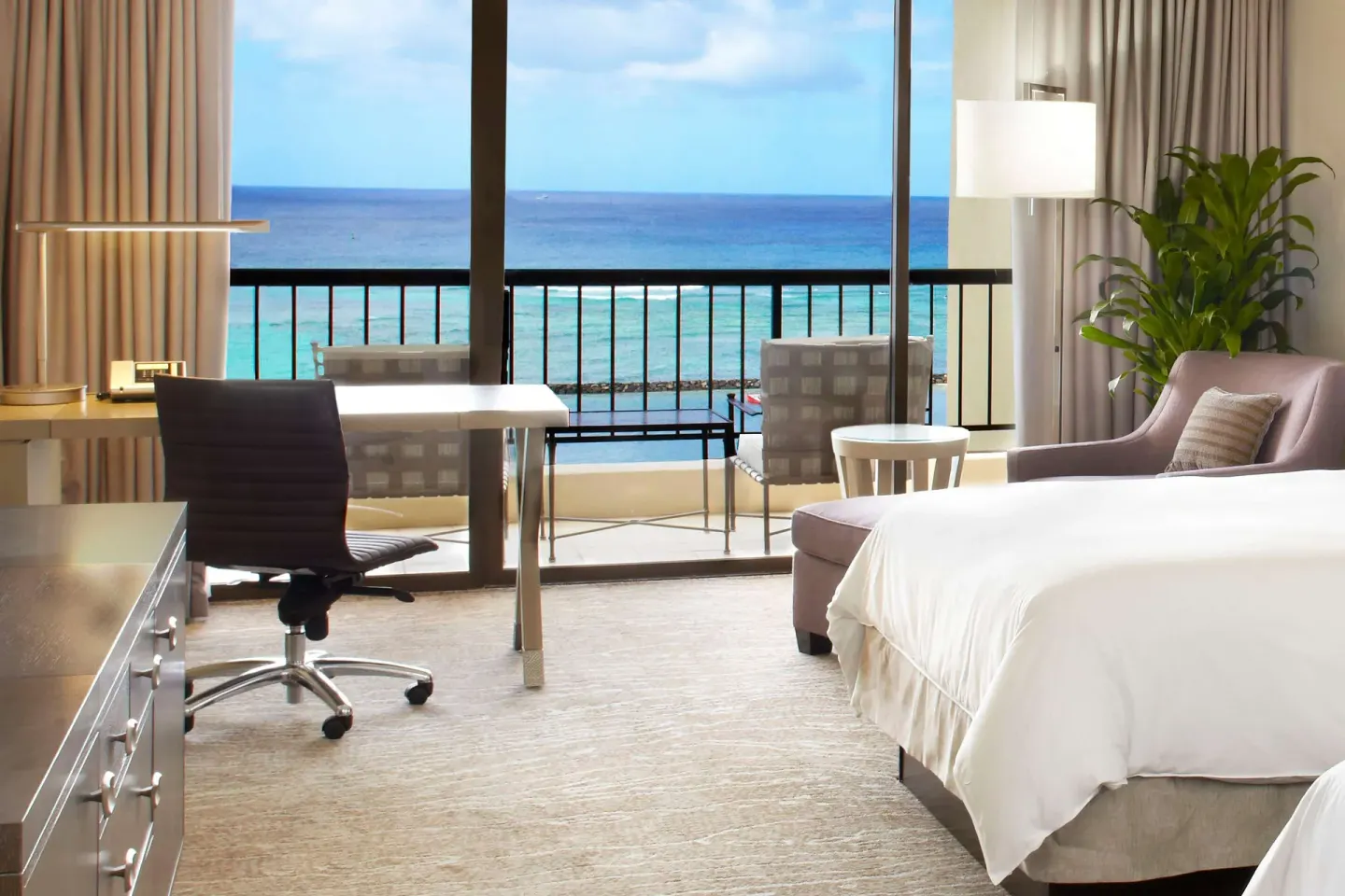 Guest room with desk, bed, balcony, and ocean view at Hilton Hawaiian Village Waikiki Beach Resort.