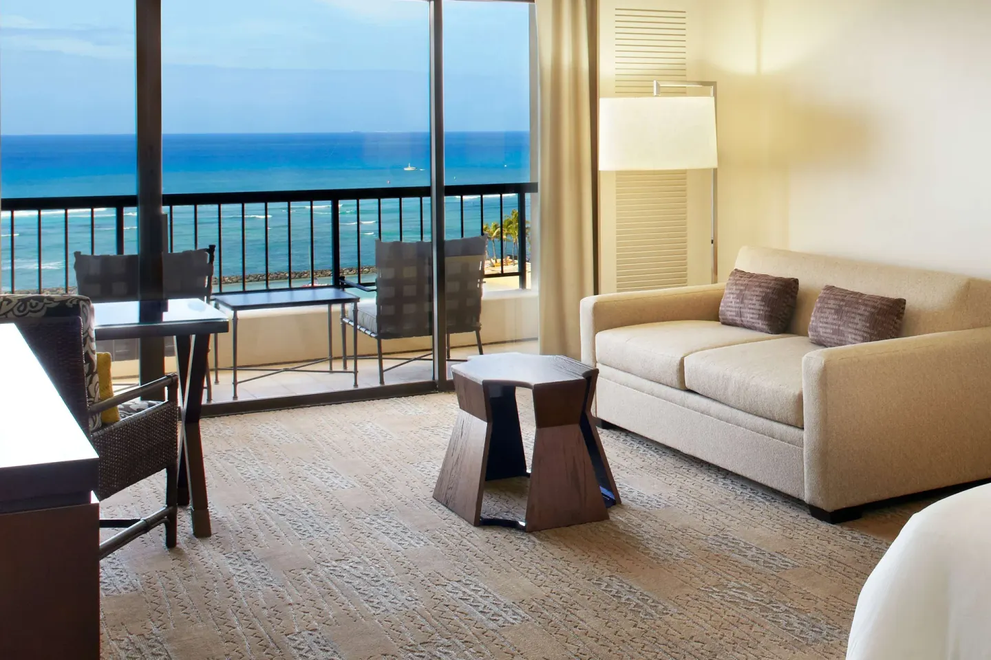 Ocean-view seating area and balcony in a guest room at Hilton Hawaiian Village Waikiki Beach Resort.