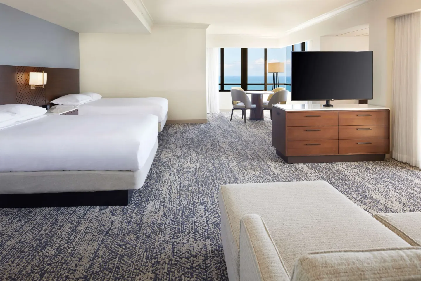 Two-bed ocean-view guest room with sitting area at Hilton Hawaiian Village Waikiki Beach Resort.