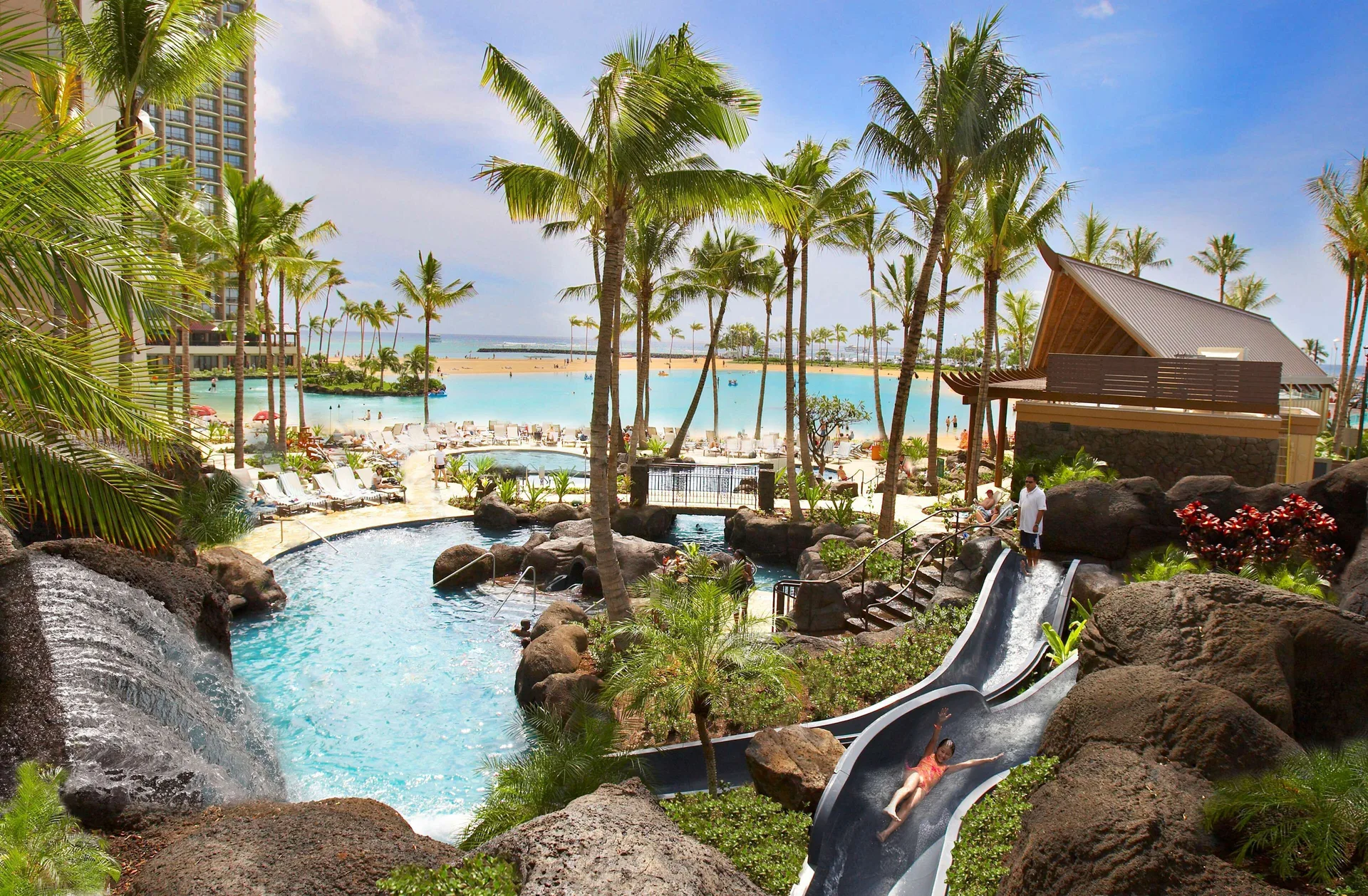 Pool slides, waterfalls, palms, and lagoon at Hilton Hawaiian Village Waikiki Beach Resort.