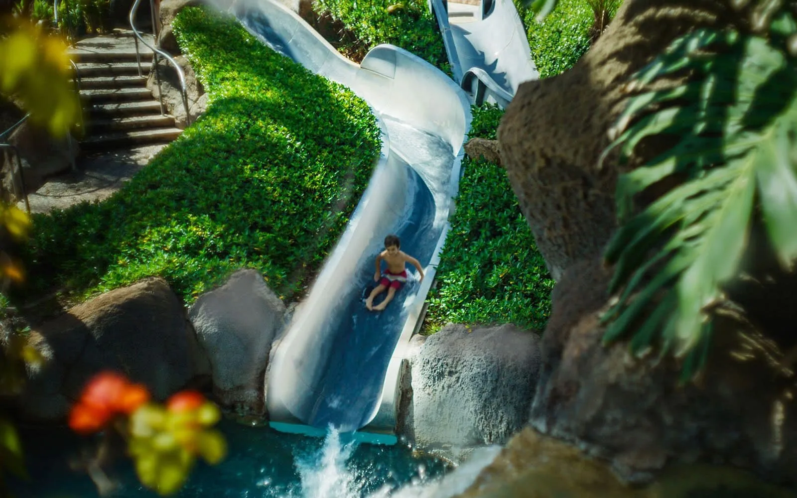 Child riding a pool waterslide at Hilton Hawaiian Village Waikiki Beach Resort.