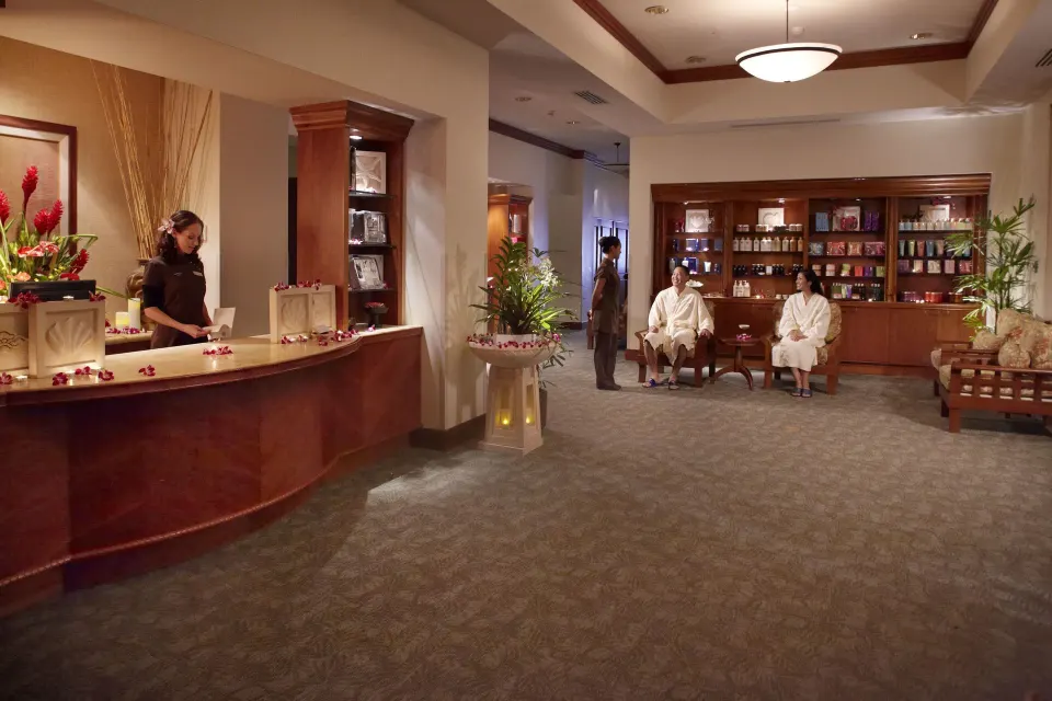 Spa lounge and retail area with seated robe-clad guests at Hilton Hawaiian Village Waikiki Beach Resort.