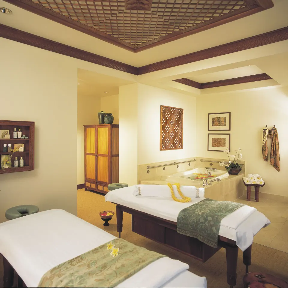 Spa treatment room with massage tables and soaking tub at Hilton Hawaiian Village Waikiki Beach Resort.