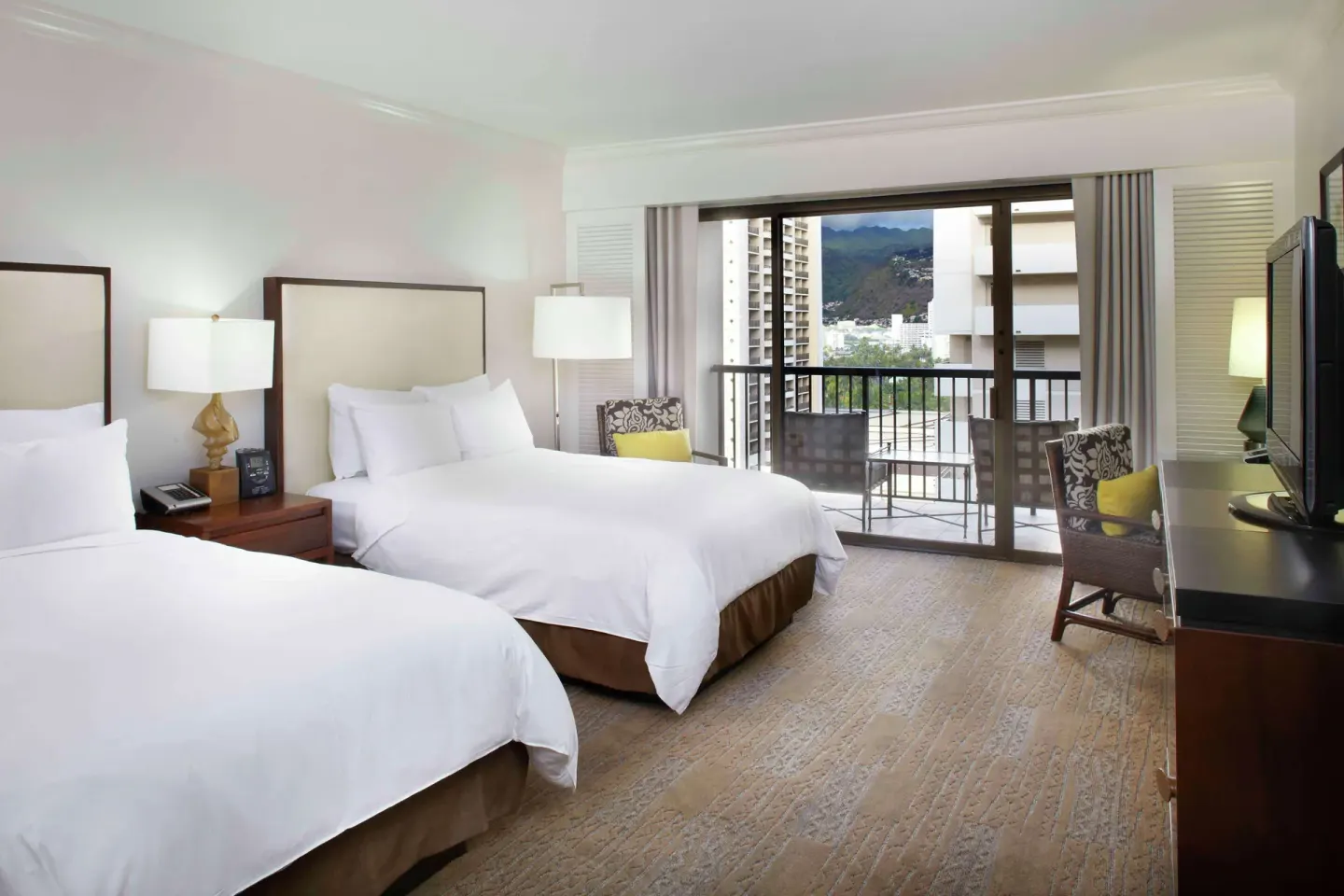 Two-bed guest room with balcony and mountain view at Hilton Hawaiian Village Waikiki Beach Resort.