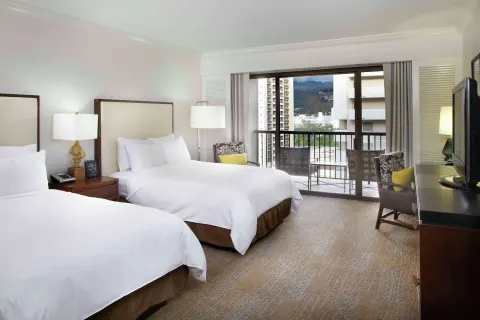Two-bed guest room with balcony and mountain view at Hilton Hawaiian Village Waikiki Beach Resort.