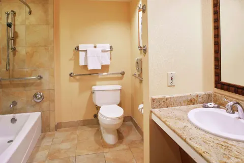 Accessible bathroom with tub, grab bars, toilet and vanity at Hilton Hawaiian Village Waikiki Beach Resort.