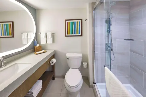 Renovated Rainbow Tower bathroom at Hilton Hawaiian Village Waikiki Beach Resort with vanity and glass shower.